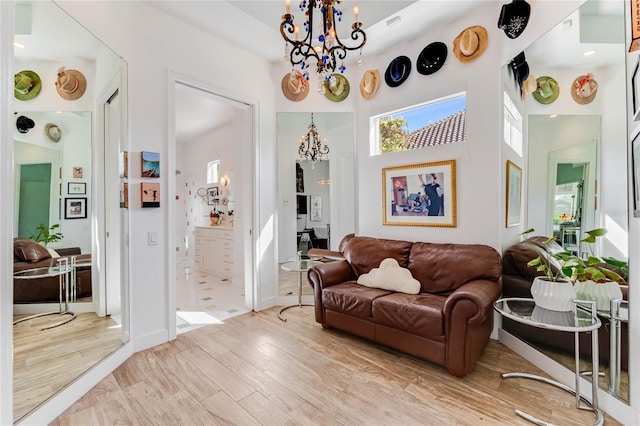 living room with light hardwood / wood-style floors and a notable chandelier