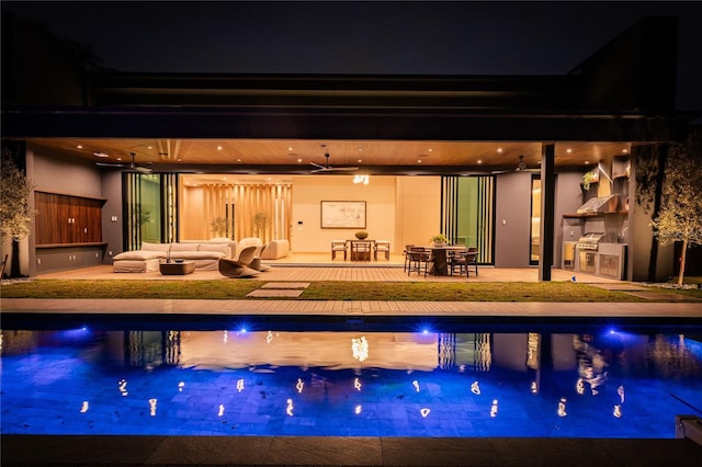 pool at twilight featuring exterior kitchen, an outdoor hangout area, ceiling fan, and a patio