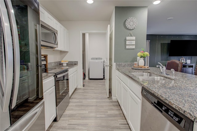 kitchen featuring sink, white cabinetry, stone counters, stainless steel appliances, and washer / clothes dryer