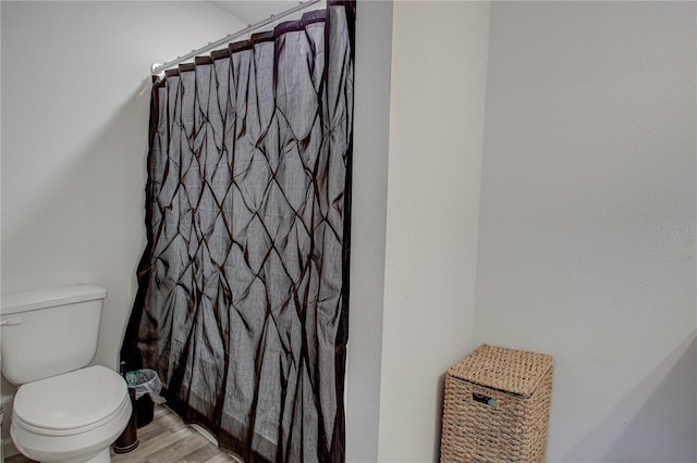 bathroom featuring hardwood / wood-style flooring, walk in shower, and toilet