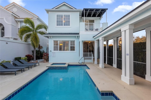 rear view of property with a swimming pool with hot tub, a patio, and a balcony