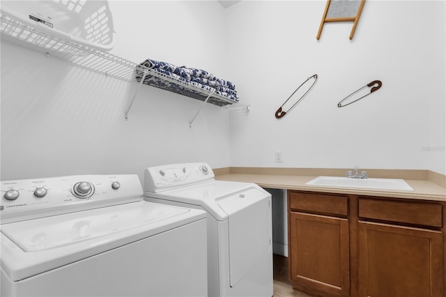 clothes washing area with cabinets, washer and clothes dryer, and sink