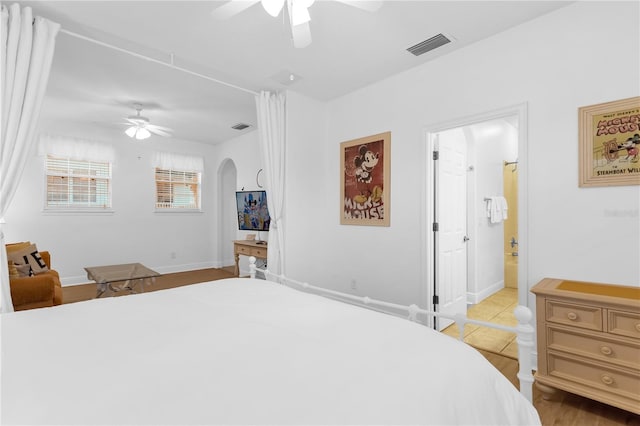 bedroom featuring ceiling fan, ensuite bathroom, and light hardwood / wood-style flooring