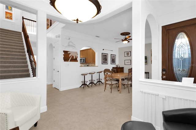 tiled foyer with ceiling fan and ornamental molding