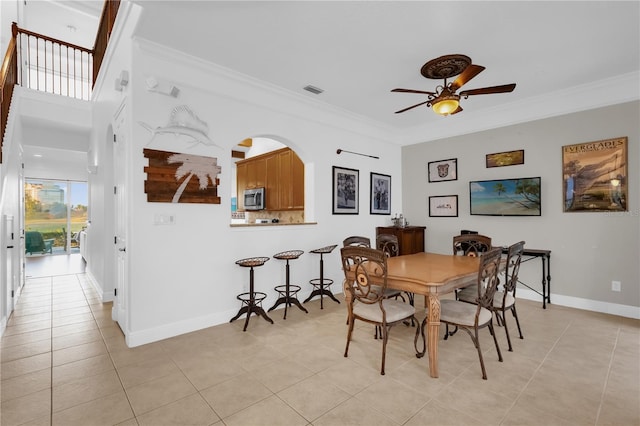 dining room with crown molding, ceiling fan, and light tile patterned floors