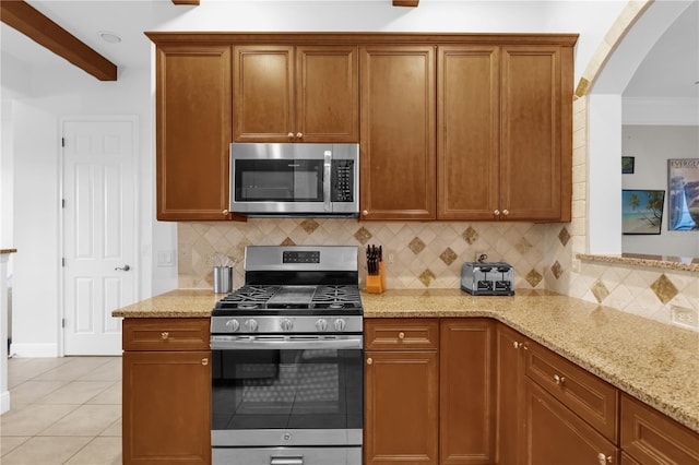 kitchen featuring decorative backsplash, light tile patterned floors, light stone counters, stainless steel appliances, and beam ceiling