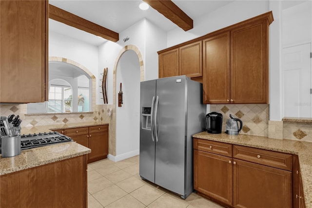 kitchen with tasteful backsplash, light stone counters, beam ceiling, and stainless steel fridge with ice dispenser