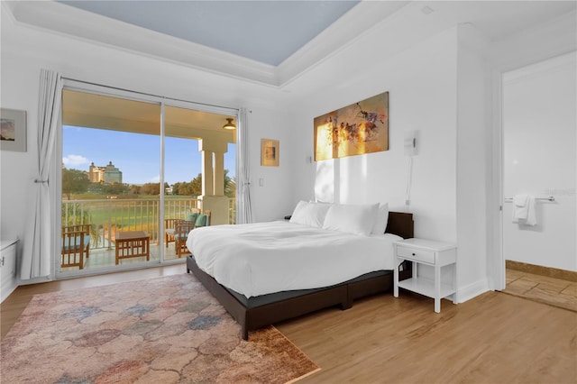 bedroom featuring hardwood / wood-style flooring, a raised ceiling, ornamental molding, and access to exterior