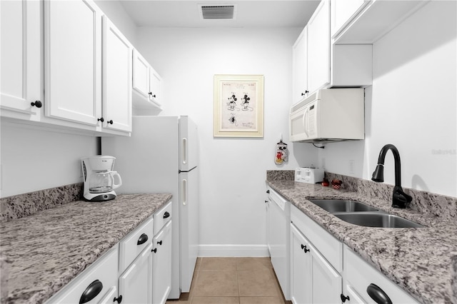 kitchen with sink, light tile patterned floors, white appliances, light stone counters, and white cabinets