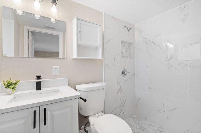 bathroom featuring vanity, tiled shower, and toilet