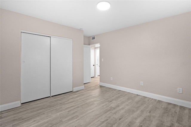 unfurnished bedroom featuring light hardwood / wood-style floors and a closet