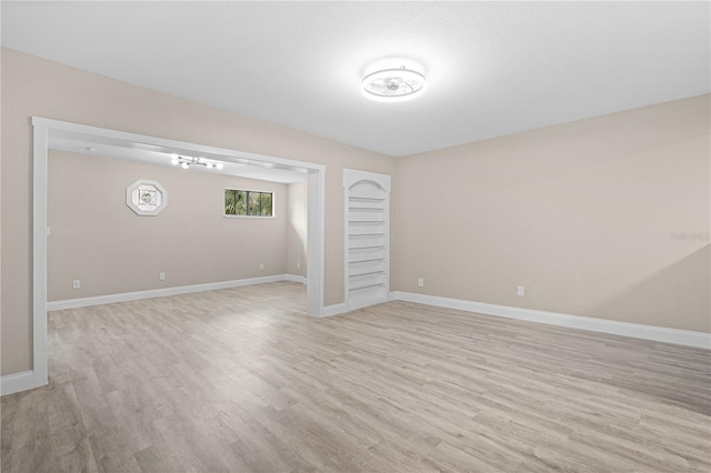 spare room with built in shelves and light wood-type flooring