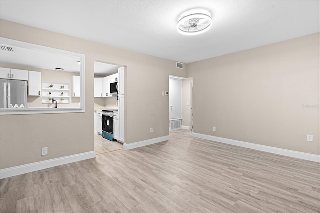 unfurnished living room with sink, built in features, and light wood-type flooring