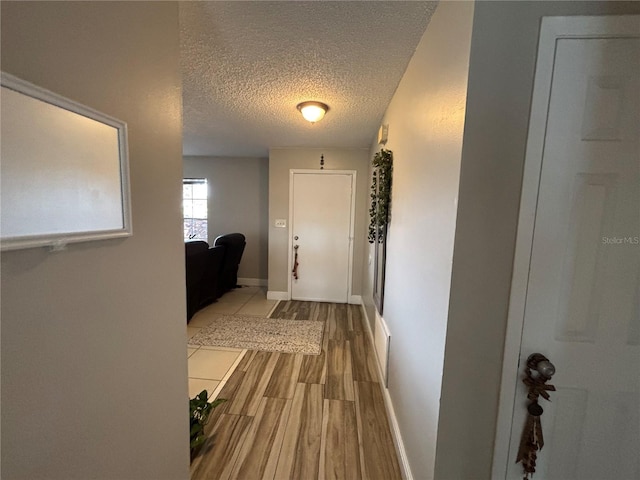 corridor with light hardwood / wood-style floors and a textured ceiling