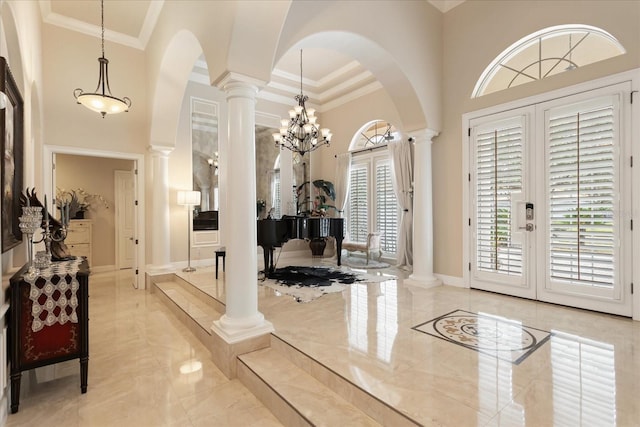 foyer with a chandelier, crown molding, a towering ceiling, and french doors