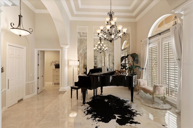 misc room with an inviting chandelier, decorative columns, a high ceiling, a tray ceiling, and crown molding