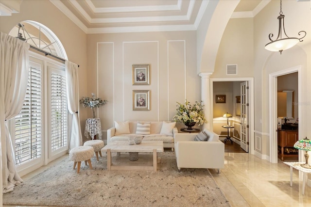 sitting room featuring crown molding, ornate columns, and a towering ceiling