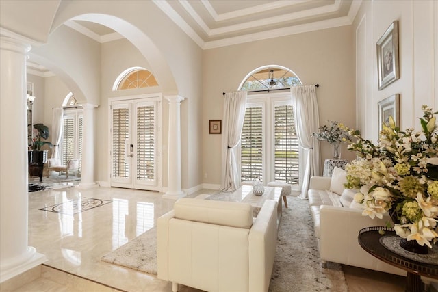 living room featuring french doors, a towering ceiling, crown molding, and decorative columns