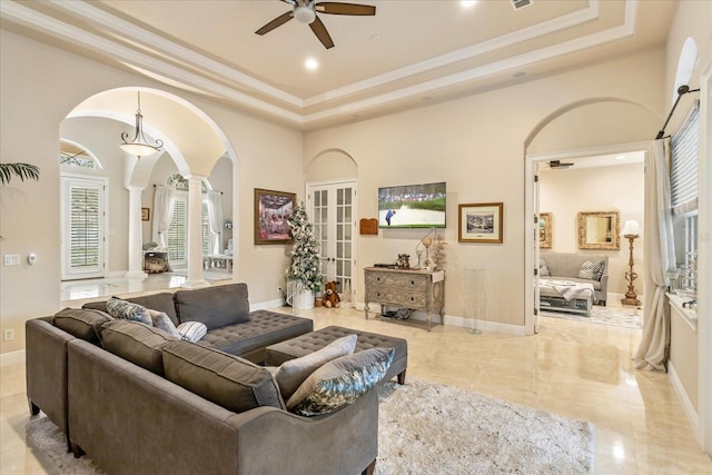 living room featuring decorative columns, french doors, a tray ceiling, and ceiling fan