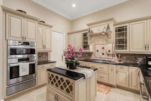 kitchen with stainless steel appliances, cream cabinetry, and tasteful backsplash