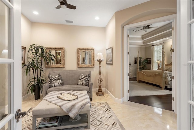 living area featuring ceiling fan and crown molding