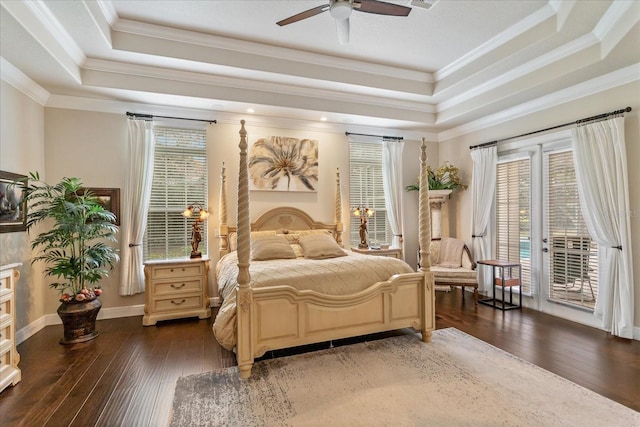 bedroom with dark wood-type flooring, access to exterior, a tray ceiling, and ceiling fan