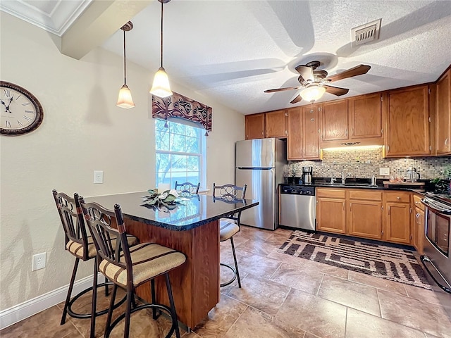 kitchen with a breakfast bar, decorative backsplash, sink, hanging light fixtures, and stainless steel appliances