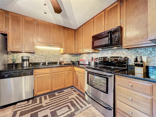 kitchen featuring sink, backsplash, appliances with stainless steel finishes, and dark stone countertops