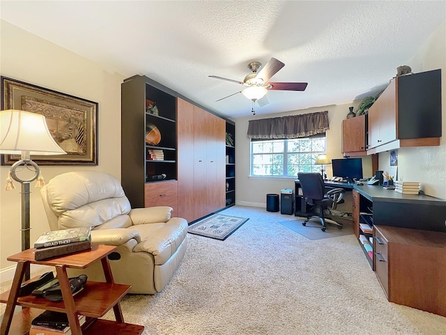 carpeted home office featuring ceiling fan and a textured ceiling