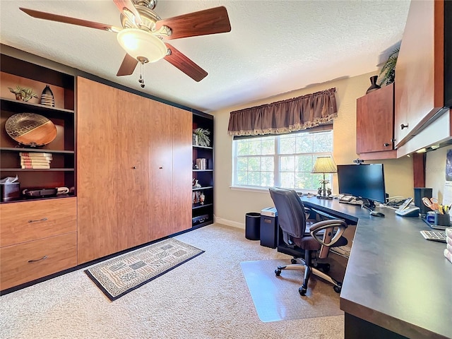 carpeted home office with a textured ceiling and ceiling fan