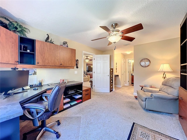 office featuring ceiling fan, light colored carpet, and a textured ceiling