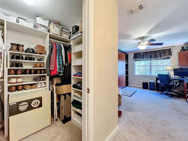 walk in closet with light carpet and ceiling fan