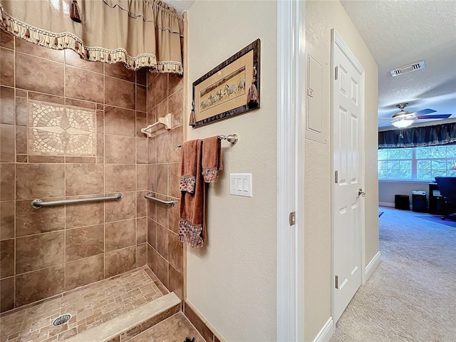 bathroom with ceiling fan, a textured ceiling, and a tile shower