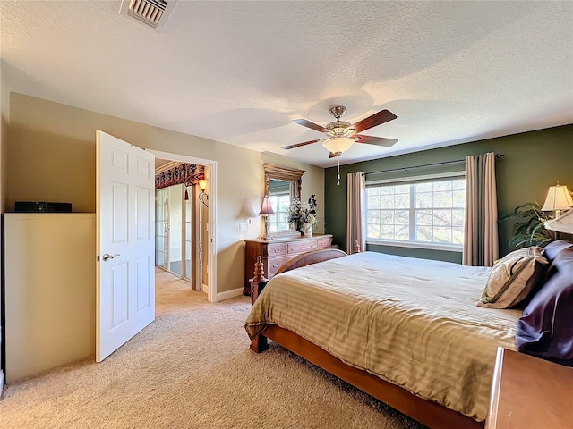 carpeted bedroom with ceiling fan and a textured ceiling