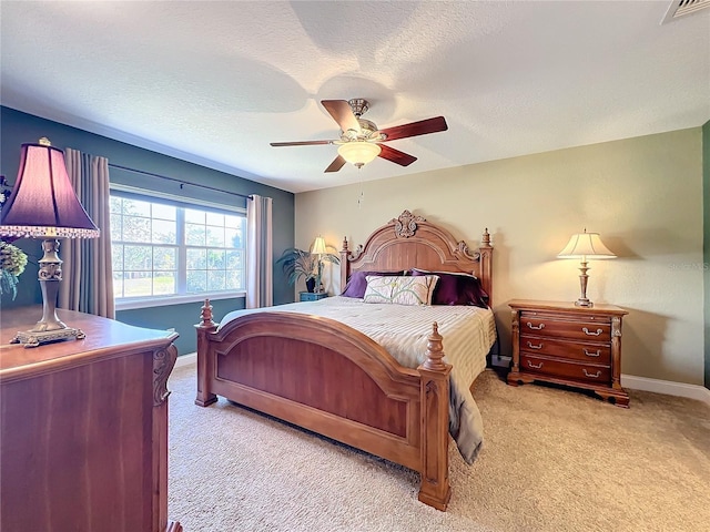 carpeted bedroom featuring ceiling fan and a textured ceiling