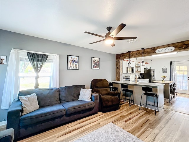 living room featuring sink, ceiling fan, and light wood-type flooring