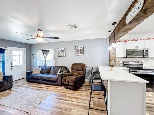 living room featuring ceiling fan, a textured ceiling, and light hardwood / wood-style floors