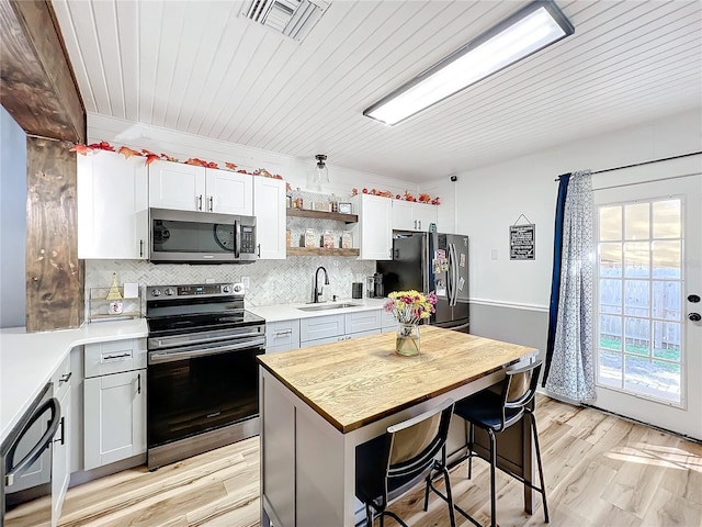 kitchen featuring a kitchen bar, sink, black appliances, a kitchen island, and white cabinets