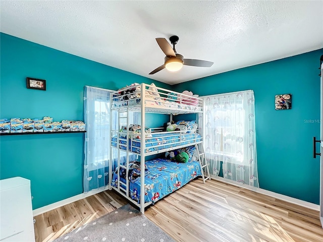 bedroom with ceiling fan, hardwood / wood-style floors, and a textured ceiling