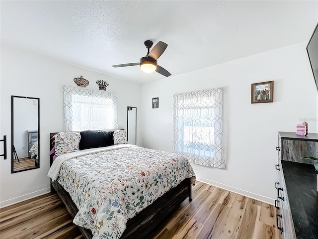 bedroom with ceiling fan, wood-type flooring, and a textured ceiling