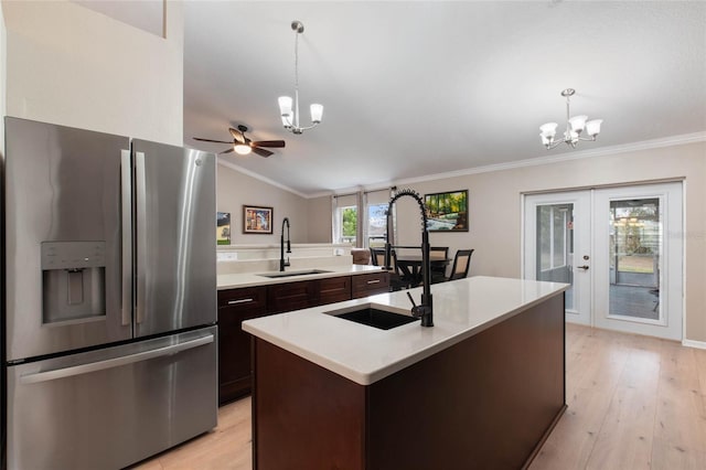 kitchen with stainless steel refrigerator with ice dispenser, a center island with sink, hanging light fixtures, and sink