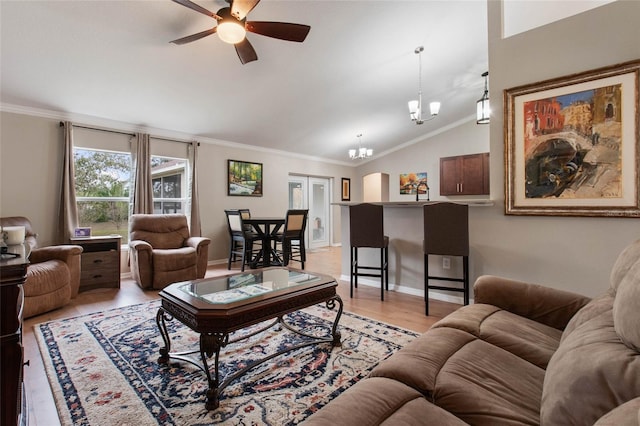 living room with lofted ceiling, ceiling fan with notable chandelier, ornamental molding, and light hardwood / wood-style floors