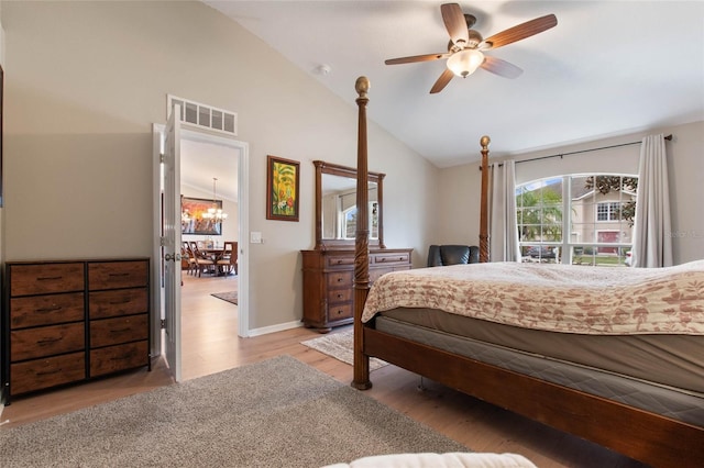 bedroom featuring vaulted ceiling, ceiling fan with notable chandelier, and light hardwood / wood-style flooring