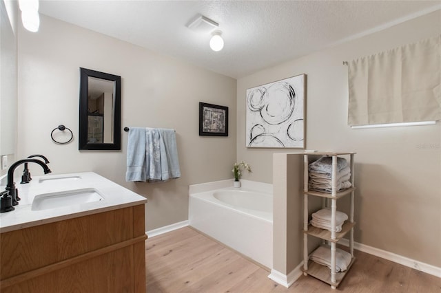 bathroom featuring vanity, a bathing tub, a textured ceiling, and hardwood / wood-style floors