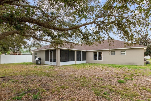 rear view of house featuring a sunroom and a lawn