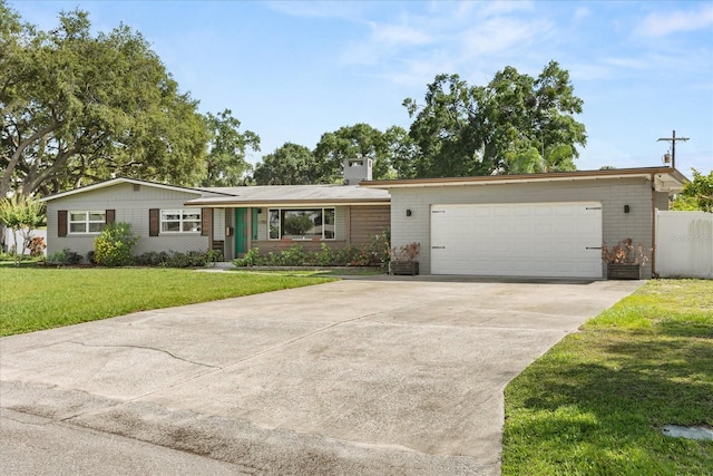 view of front of home featuring brick siding, a chimney, driveway, a front yard, and an attached garage