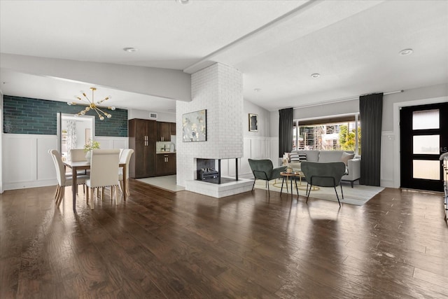 living area with vaulted ceiling, a decorative wall, wood finished floors, wainscoting, and a fireplace