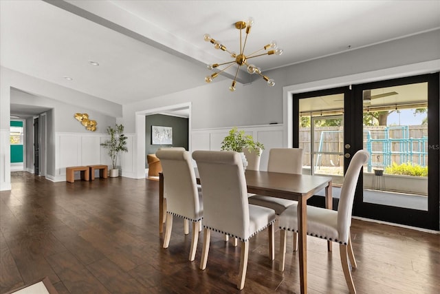 dining area featuring french doors, a decorative wall, a chandelier, dark wood finished floors, and a wainscoted wall