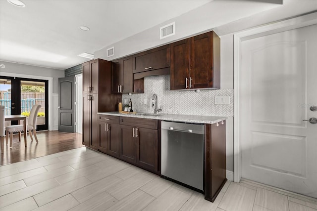 kitchen with dishwasher, a sink, dark brown cabinets, backsplash, and light stone countertops