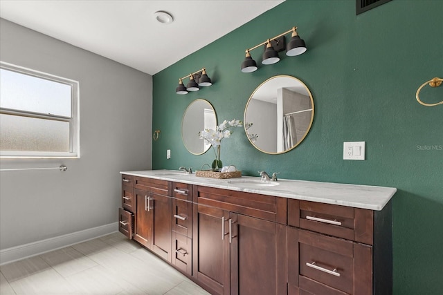 full bath featuring baseboards and double vanity